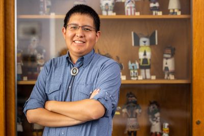 NAU student, Ryan Gilbert, poses in front of indigenous artifacts.