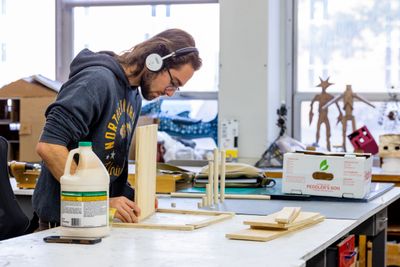 An NAU art and design student listens to music while working on a shop project.