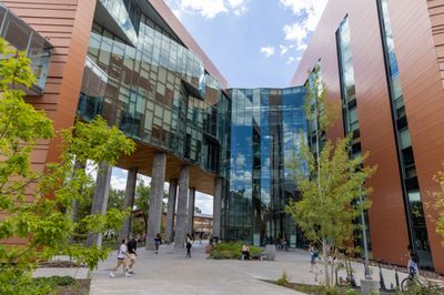 Students walking by and sitting outside of the NAU Science and Health building.