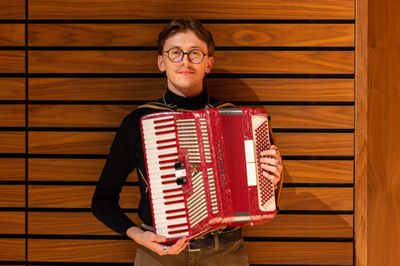 Will Whitten poses for a portrait with an accordion musical instrument.