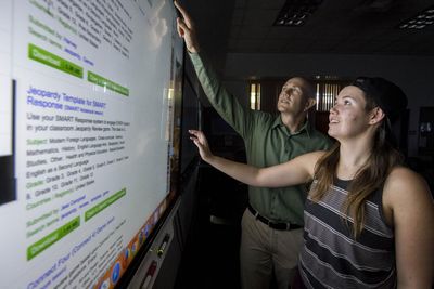 A professor and student work on a interactive white board.