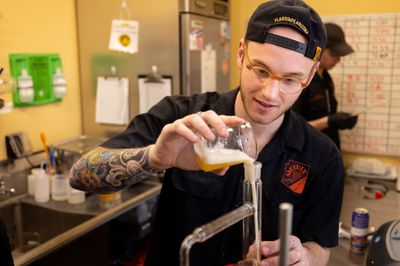 A brewer at Mother Road Brewing pours liquid into a measuring device.
