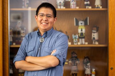 NAU student, Ryan Gilbert, poses in front of indigenous artifacts.