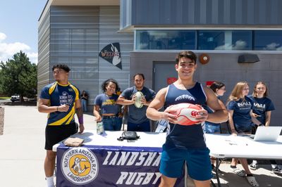 Several students standing around a booth advocating for their club at NAU's Club Fair.